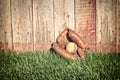 Old baseball mitt and ball on grass against wooden fence Royalty Free Stock Photo