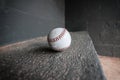 an old baseball sitting in a corner on the floor by itself