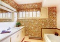 Old bathroom with floral pattern wallpaper, white cabinets and b