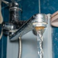 Old Bathroom Sink Faucet contaminated with calcium and grime. Hard water flows from an old tap aerator Royalty Free Stock Photo