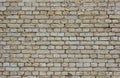 Old battered gray brick wall with dark cement and holes in bricks. rough surface texture