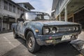 An old, battered and rusty Japanese pickup truck DATSUN close-up on the street in Thailand, in the old town of Takua Pa