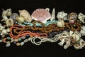 Old beads of turquoise, red coral, amber, garnet stone, multi-colored agate, pearls among various shells on black background Royalty Free Stock Photo