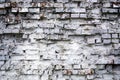 Old, beaten, white brick wall with many rockfalls and cracks