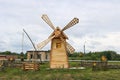 Old beautiful wooden rustic mill for grinding grain. A traditional miller with large blades in a village with a well