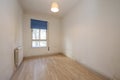 Old bedroom with a small aluminum window with a blue shutter, walls in need of a coat of paint and laminated flooring Royalty Free Stock Photo