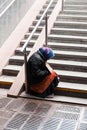 Old beggar woman sits on the stairs