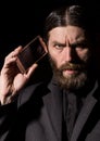 Old believer senior priest with a smartphone, bearded old man is calling on a dark background