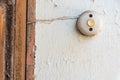 An old bell button on a white crumbling facade