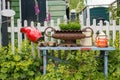 Old bench with pots, watering can and flowers in the backyard. Cozy village garden with plants, bench and white fence. Royalty Free Stock Photo