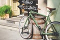 Old bicycle against coffeehouse on sunny day