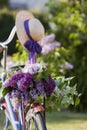 Old bicycle with bouquet of blossoming lilac and straw ladys hat outdoor in the park. Spring natural background