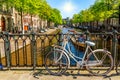 Old bicycle on the bridge in Amsterdam, Netherlands against a canal during summer sunny day. Amsterdam postcard iconic view. Royalty Free Stock Photo