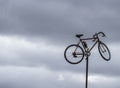 Old bicycle hanging on iron pipe against cloudy autumn sky cobweb-covered handlebars and wheels, view from below Royalty Free Stock Photo