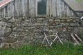 An old bicycle leaning against the stone wall of a weathered farm building