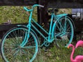 An old bicycle, painted in a bright solid color, stands by the fence as a decorative element