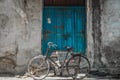 An old bicycle parked outside in front of an old vintage blue wooden- closed door of an old house in Jodhpur, Rajasthan, India.