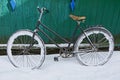 Old bicycle in the snow near the green wall Royalty Free Stock Photo