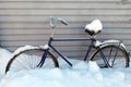 old bicycle under the snow on the background of a metal wall