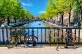 Old bicycles on the bridge in Amsterdam, Netherlands against a canal and old buildings during summer sunny day. Amsterdam postcard Royalty Free Stock Photo