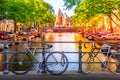 Old bicycles on the bridge in Amsterdam, Netherlands against a canal and old buildings during summer sunny day sunset. Amsterdam Royalty Free Stock Photo