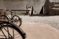 Old bicyle wheels in street in small town with group four youth in distance on jetty