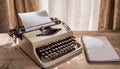 Old biege typewriter sits on desk in front of window