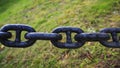 Old Big Chain. Large black metal chain on green grass background Royalty Free Stock Photo