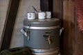 Old big thermos for drinks with a tap and mugs. Kitchen accessories for collective nutrition. Royalty Free Stock Photo