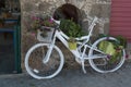 Old bike. Decorated with pots of flowers. Painted in white.