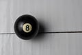 Old billiard ball number 8 black color on white wooden table background, copy space Royalty Free Stock Photo