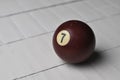 Old billiard ball number 7 brown color on white wooden table background, copy space Royalty Free Stock Photo