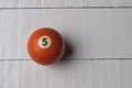 Old billiard ball number 5 orange color on white wooden table background, copy space Royalty Free Stock Photo