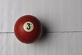 Old billiard ball number 3 red color on white wooden table background, copy space Royalty Free Stock Photo