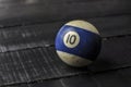 Old billiard ball number 10 striped white and blue on black wooden table background, copy space