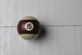 Old billiard ball number 15 striped white and brown on white wooden table background, copy space Royalty Free Stock Photo