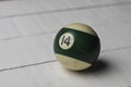 Old billiard ball number 14 striped white and green on white wooden table background, copy space Royalty Free Stock Photo
