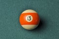 Old billiard ball number 13 striped white and orange on green billiard table, copy space Royalty Free Stock Photo
