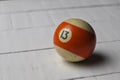 Old billiard ball number 13 striped white and orange on white wooden table background, copy space Royalty Free Stock Photo