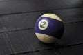 Old billiard ball number 12 striped white and purple on black wooden table background, copy space Royalty Free Stock Photo