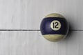 Old billiard ball number 12 striped white and purple on white wooden table background, copy space Royalty Free Stock Photo