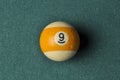 Old billiard ball number 9 striped white and yellow on green billiard table, copy space Royalty Free Stock Photo