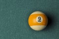 Old billiard ball number 9 striped white and yellow on green billiard table, copy space Royalty Free Stock Photo
