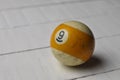 Old billiard ball number 9 striped white and yellow on white wooden table background, copy space Royalty Free Stock Photo
