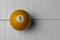 Old billiard ball number 1 yellow color on white wooden table background, copy space Royalty Free Stock Photo