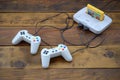 Old 8-bit video game console with game cartridge and two gaming joysticks on wooden background Royalty Free Stock Photo