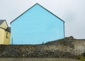 Exterior blue walled building beside yellow house and old stone wall