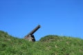 Old black cannon in wooden base on green grass hill on the background of cloudless blue sky Royalty Free Stock Photo