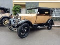 Old cream 1930s Ford Model A double phaeton convertible parked in the street. Classic car show.