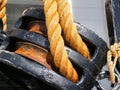 Old black double pulley with strong rope closeup.